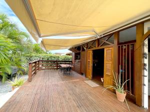 una terraza de madera con una sombrilla de patio en una casa en La Bitasyon Tirisyl, en Capesterre