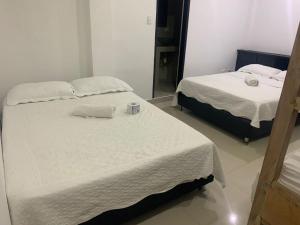 a bedroom with two beds with white sheets and a mirror at Hotel Las Gaviotas in San Andrés