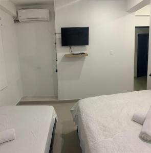 a room with two beds and a tv on a wall at Hotel Las Gaviotas in San Andrés