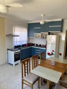 a kitchen with blue cabinets and a table and chairs at Casa Térrea - Nova Itanhaém in Itanhaém