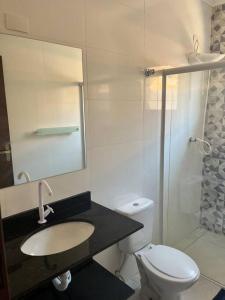 a bathroom with a toilet and a sink and a mirror at Casa Térrea - Nova Itanhaém in Itanhaém +22 photos