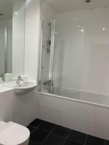 een badkamer met een douche, een toilet en een wastafel bij Spacious flat next to central station in Glasgow