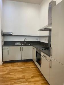 een keuken met witte apparatuur en een houten vloer bij Spacious flat next to central station in Glasgow