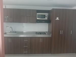 a kitchen with wooden cabinets and a microwave and a sink at Apartamentos Turísticos en Laureles- Estadio, Medellin in Medellín