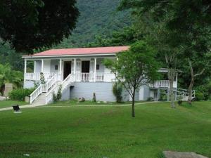 a white house with a red roof and a yard at Jayuya Cozy Aparment with Wi-Fi, Free Parking and AC in Jayuya