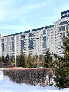 a large apartment building with snow in front of it at 452 Возле Байтерека для компании 1-6 человек с 2 кроватями и диваном in Astana