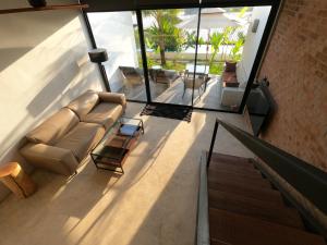 a living room with a couch and glass walls at Sky Lofts Phuket in Nai Yang Beach