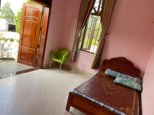 a bedroom with a bed and a green chair at Mekong Cantho Homestay in Can Tho