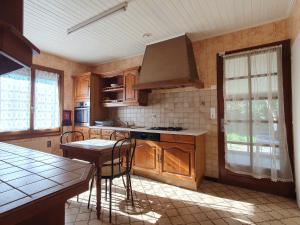 una cocina con armarios de madera y una mesa con sillas. en Maison L'Aiguillon-sur-Mer, 5 pièces, 6 personnes - FR-1-476-135, en LʼAiguillon-sur-Mer