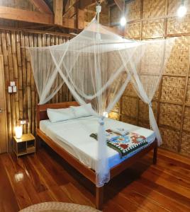 a bedroom with a bed with a mosquito net at Kahoy Cottages in Siquijor