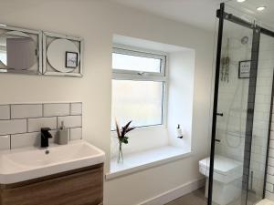 a white bathroom with a sink and a window at Hardy Hideaway in Ulverston