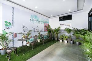 Zimmer mit Pflanzen, Tischen und Stühlen in der Unterkunft Nevesa Inn in Bangalore
