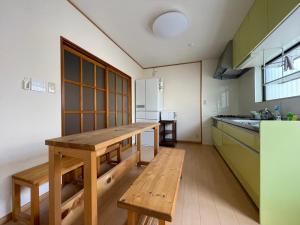 uma cozinha com uma mesa de madeira e um banco em 道後の家 em Matsuyama