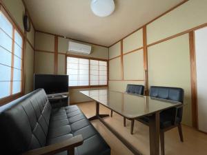 uma sala de conferências com uma mesa de vidro e cadeiras em 道後の家 em Matsuyama