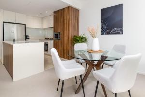 a dining room with a glass table and white chairs at Spacious 1-Bed with View in Central Location in Canberra