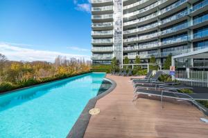 a large apartment building with a swimming pool and lounge chairs at Spacious 1-Bed with View in Central Location in Canberra