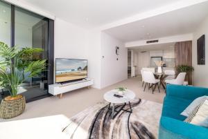 sala de estar con sofá azul y TV en Spacious 1-Bed with View in Central Location, en Canberra