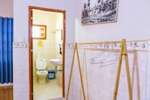 a bathroom with a toilet and a painting on the wall at Le Tonle in Kratie