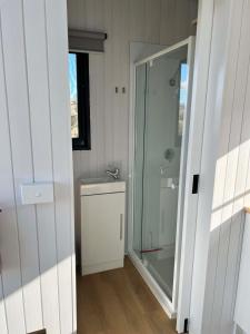 a bathroom with a glass shower and a sink at Willow Three Tiny House in Willow Tree