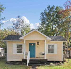 una pequeña casa amarilla con una puerta azul en Bay Cottage!, en Chickasaw