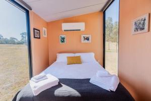 a small bedroom with a bed and a large window at Hermano Farm Stay 