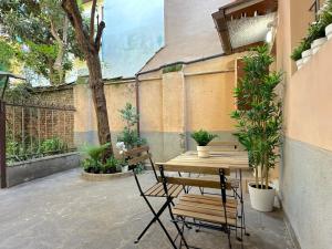 a patio with a wooden table and chairs and plants at Mascarella Boutique Apartment in Bologna