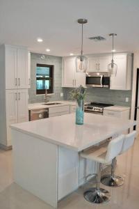 a kitchen with white cabinets and a white counter top at Stylish home in Dania Beach