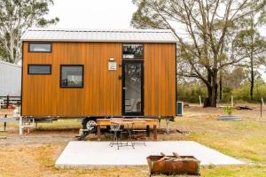 une petite maison dans un champ avec une table dans l'établissement Odyssean Tiny House, à Cessnock