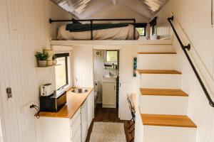 uma pequena casa com um lavatório e uma cama em Odyssean Tiny House em Cessnock