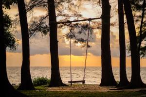 a swing hanging from trees in front of the ocean at Le Méridien Phuket Mai Khao Beach Resort in Mai Khao Beach