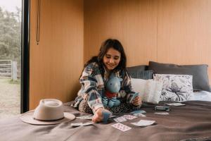 Una donna seduta su un letto con un mucchio di carte da gioco di The Wollombi Wanderer a Wollombi