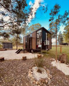 a tiny house in a field with trees at Kawal Tiny House in Wollombi