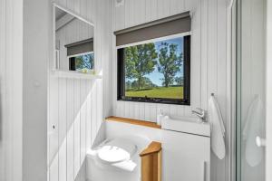 a white bathroom with a toilet and a window at Valley Escape in Rothbury