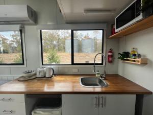 a kitchen with a counter with a sink and two windows at Yellow Rock Views in Broke
