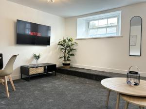 a living room with tables and a tv on the wall at Hardy Hideaway in Ulverston