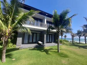 una casa con palme di fronte all'oceano di Starlight Villa Beach Resort a Phan Thiet