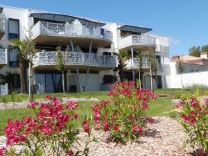 a building with pink flowers in front of it at Appartement luxe avec piscine, animaux admis, climatisation et parking à La Tranche-sur-Mer - FR-1-194-227 in La Tranche-sur-Mer