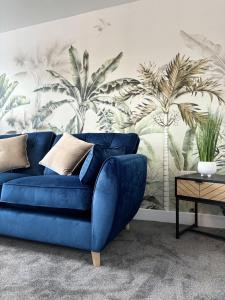 a blue couch in a living room with a palm mural at Hardy Hideaway in Ulverston