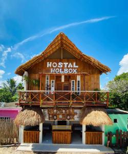 uma casa de madeira com uma varanda na frente em HOLBOX HOSTAL em Ilha Holbox