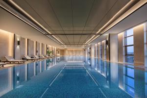 a swimming pool with chairs in a building at Sofitel Xiong An in Baoding