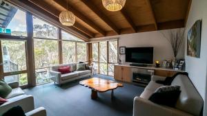 a living room with couches and a tv and a table at Tanjil Creek Lodge in Baw Baw Village