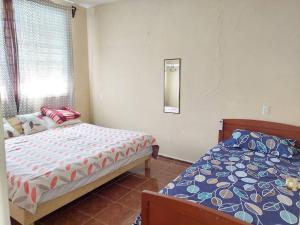 sypialnia z 2 łóżkami, oknem i lustrem w obiekcie La casa del descanso w mieście Catemaco