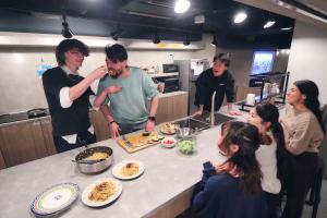 a group of people in a kitchen preparing food at &AND HOSTEL SHINSAIBASHI EAST in Osaka