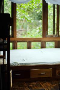 a bed in front of a window in a room at Tini Wood House in Hue