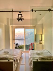 two beds in a room with a large window at Stunning Taal View Staycation in Tagaytay in Tagaytay