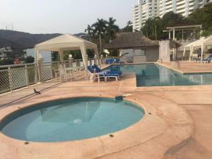 a large swimming pool with chairs and a building at Cómodo departamento en Costa Azul. in Acapulco