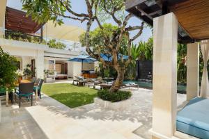 eine Außenterrasse mit einem Baum und einem Haus in der Unterkunft Villa Camellia by Nakula in Jimbaran + 12 Fotos