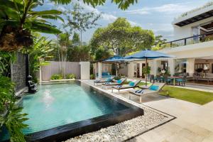 ein Bild eines Swimmingpools mit Stühlen und Sonnenschirmen in der Unterkunft Villa Camellia by Nakula in Jimbaran