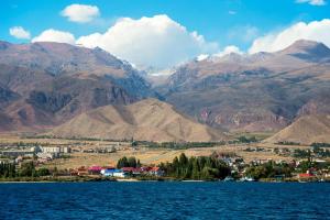 a town on the shore of a lake with mountains at Гостевой дом Ак-Толкун in Cholpon-Ata