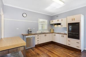 una cocina con armarios blancos y un reloj en la pared en Place au Soleil, en Coffs Harbour